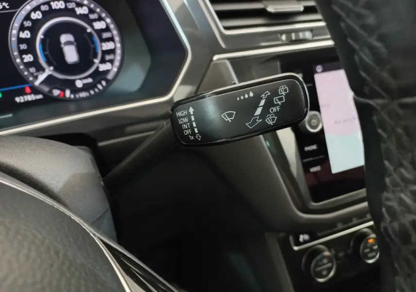 Gros plan sur la commande des essuie-glaces à gauche du volant dans l'habitacle noir du Volkswagen Tiguan Allspace marron 2018.