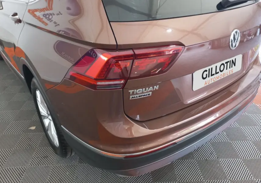 Vue 3/4 arrière droite d'un Volkswagen Tiguan Allspace marron avec feux arrière LED et logo visible