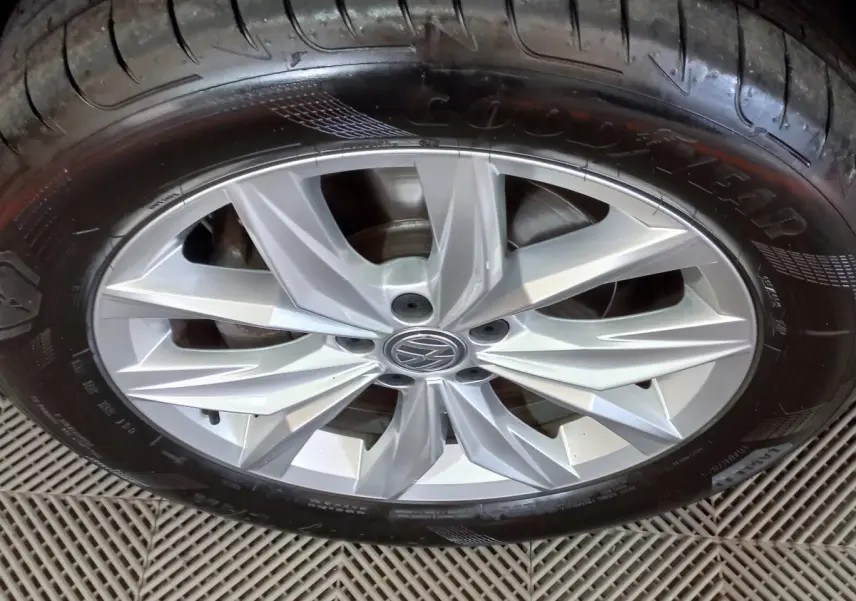 Gros plan sur la jante argentée avec logo Volkswagen d'un Tiguan Allspace marron, pneu Goodyear visible.