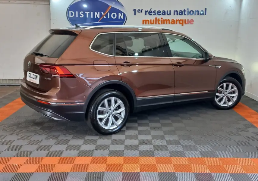 Vue latérale droite du Volkswagen Tiguan Allspace marron 2018 en intérieur, soulignant ses jantes alliage et lignes élégantes.
