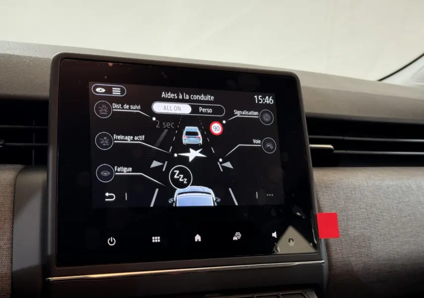 Écran tactile central affichant les aides à la conduite dans l'habitacle d'une Renault Clio gris clair, vue de face.