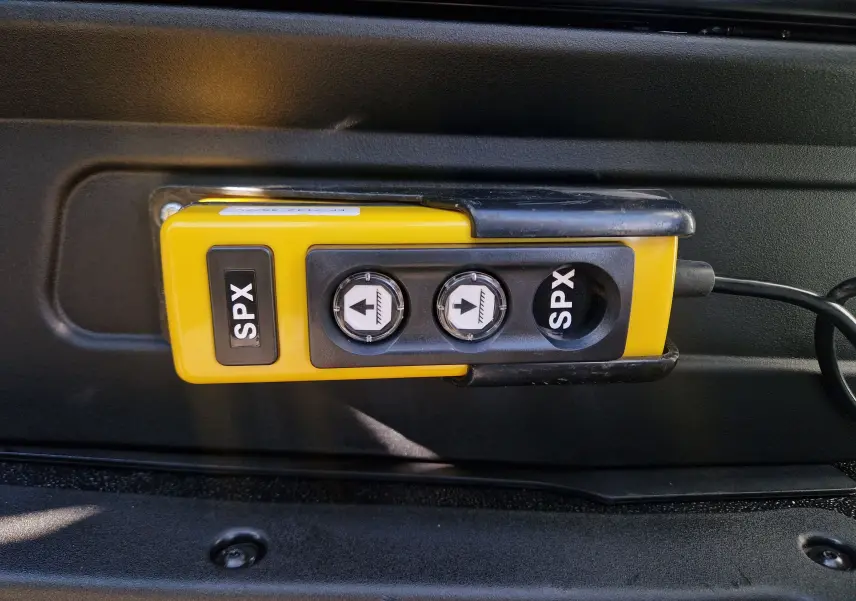 Gros plan sur la commande jaune SPX avec deux boutons fléchés, fixée à l'intérieur d'un Iveco Daily Chassis Cabine blanc.