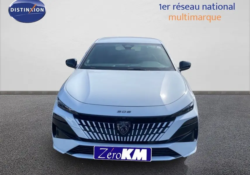 Vue frontale d'une Peugeot 308 blanche Okenite Metal avec calandre noire distinctive et logo lion central.