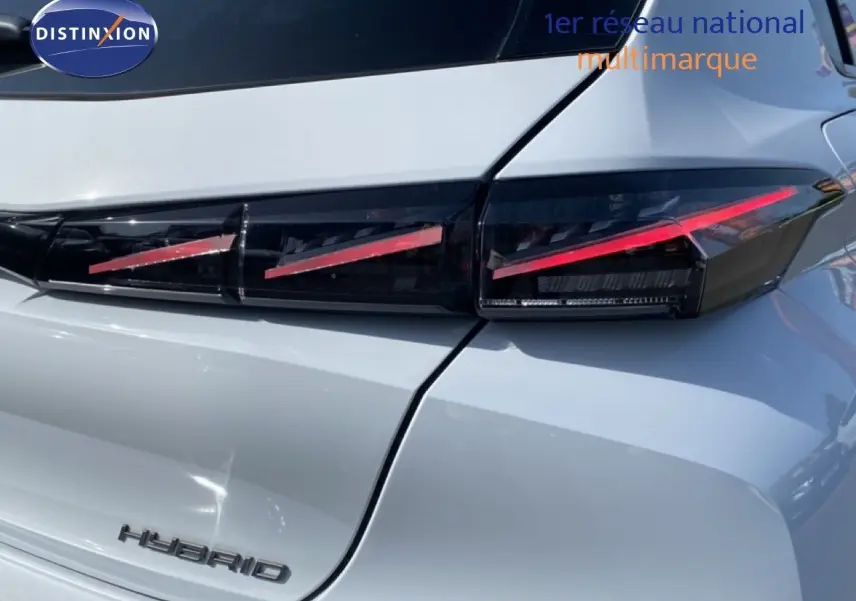 Gros plan sur le feu arrière droit rouge et noir d'une Peugeot 308 hybride blanche Okenite 2026.