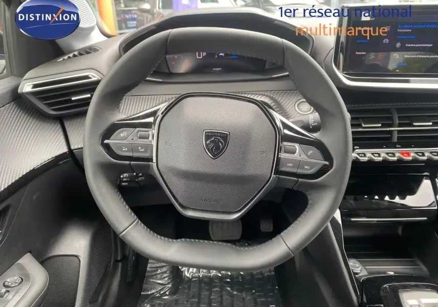 Vue centrée sur le volant cuir noir de la Peugeot 208 Hybrid 2026 avec tableau de bord et écran tactile visibles.