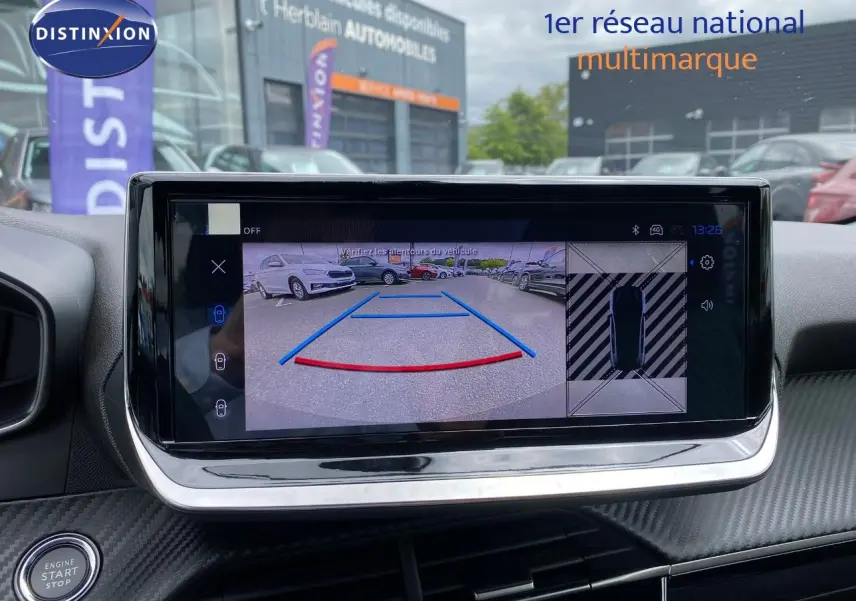 Écran tactile intérieur montrant la caméra de recul d'une Peugeot 208 gris selenium metal en stationnement.