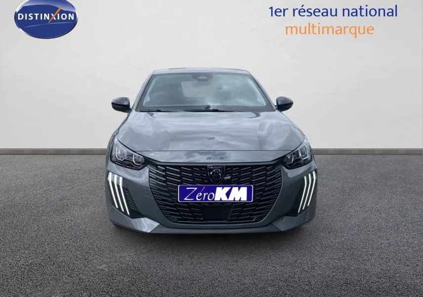 Peugeot 208 Hybrid gris sélénium métal vue de face avec calandre noire et feux LED distinctifs allumés.
