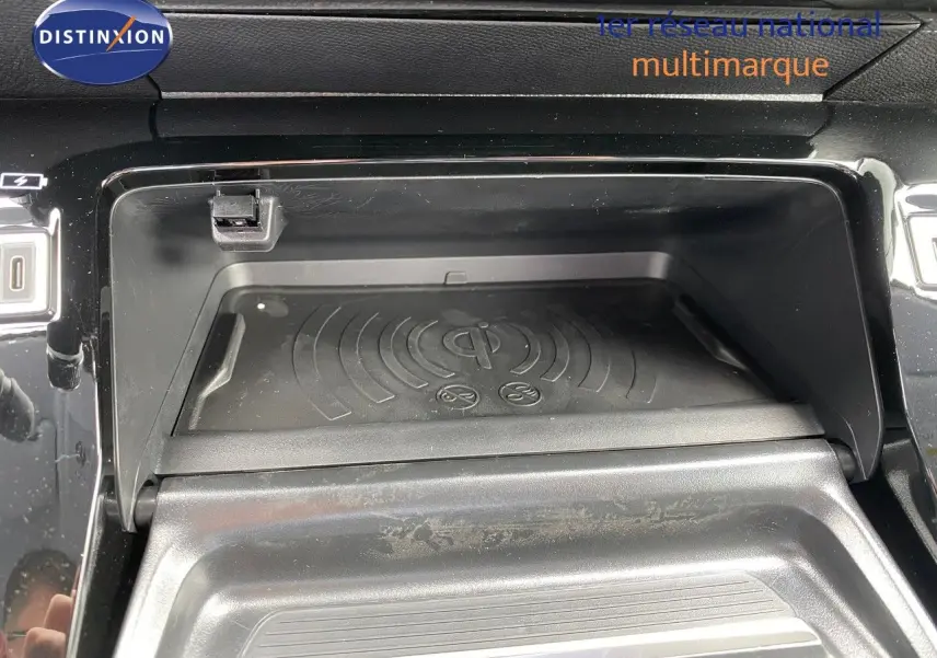Gros plan sur le compartiment de recharge sans fil du Peugeot 208 gris sélénium, intérieur noir brillant.