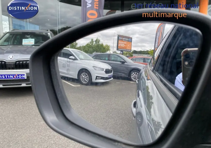 Rétroviseur montrant le côté droit d'une Peugeot 208 gris selenium metal en stationnement, reflet partiel du véhicule.