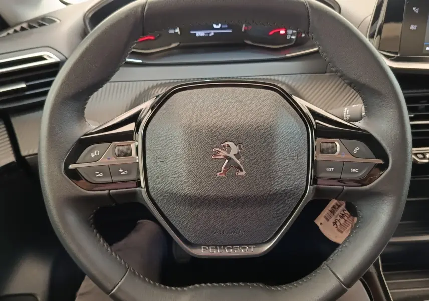 Vue rapprochée du volant cuir noir de la Peugeot 208 PureTech 75 S&S Style 2023 avec commandes intégrées.