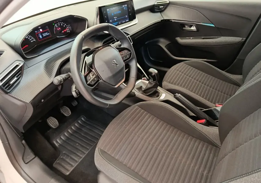 Vue intérieure côté conducteur de la Peugeot 208 PureTech 75 S&S Style 2023, volant cuir, tableau de bord moderne noir.