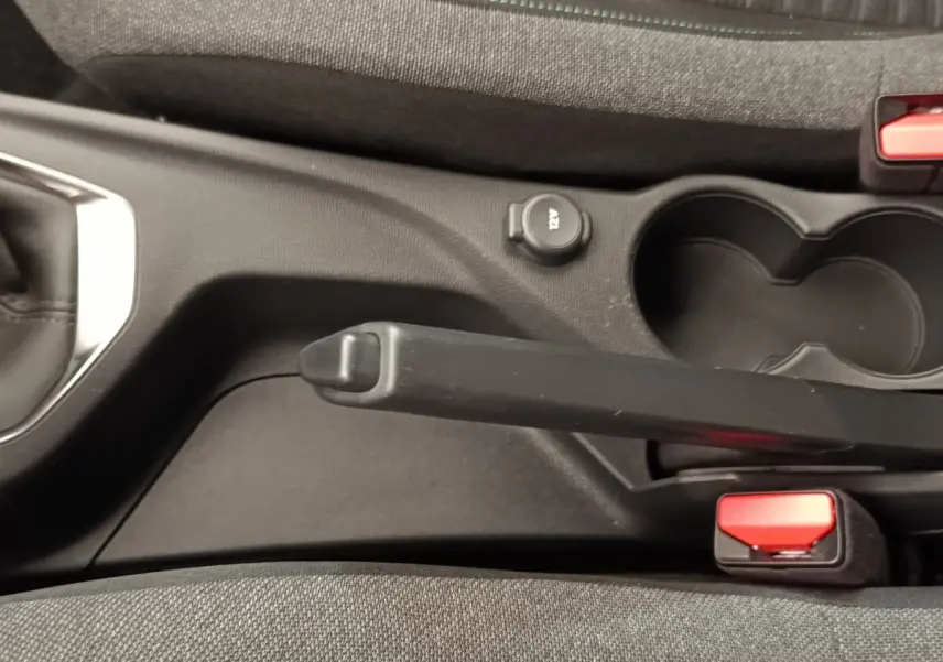 Vue rapprochée de la console centrale noire et tissu gris avec frein à main et prise 12V de la Peugeot 208 2023.