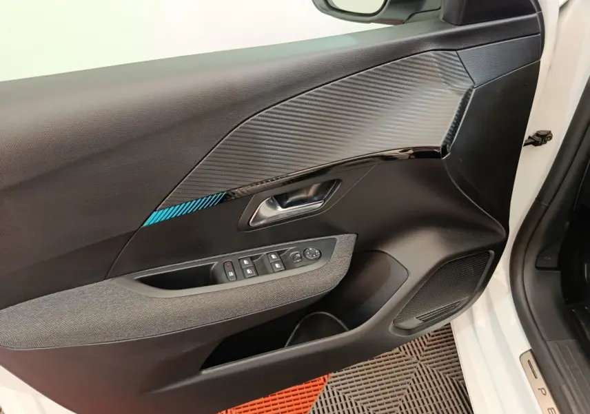 Vue rapprochée de la porte avant gauche blanche d’une Peugeot 208 avec insert décoratif noir et bleu et commandes électriques.