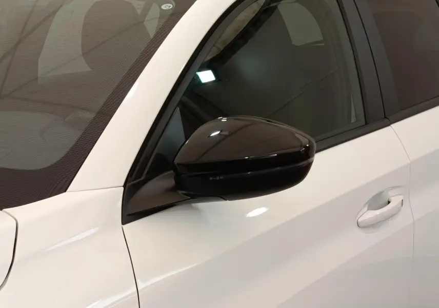 Gros plan sur le rétroviseur noir et la portière blanche côté conducteur d'une Peugeot 208 2023 PureTech Style.