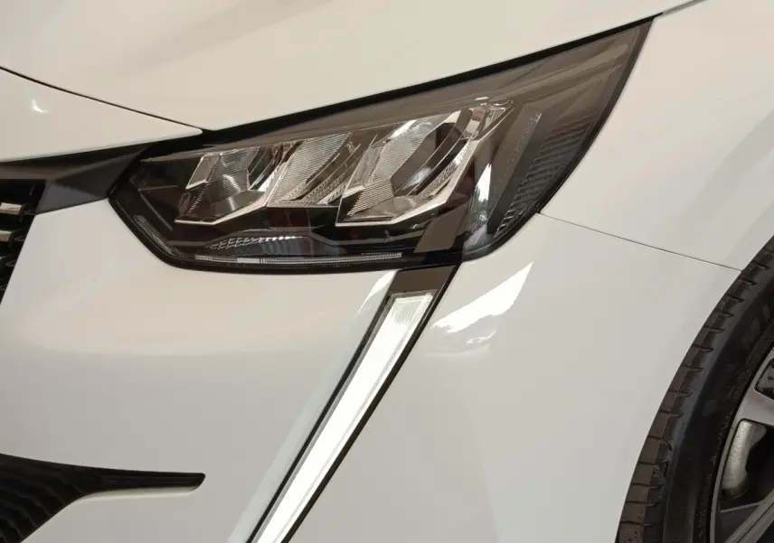 Gros plan sur le phare avant gauche blanc du Peugeot 208 2023 avec feu de jour LED en forme de griffes.
