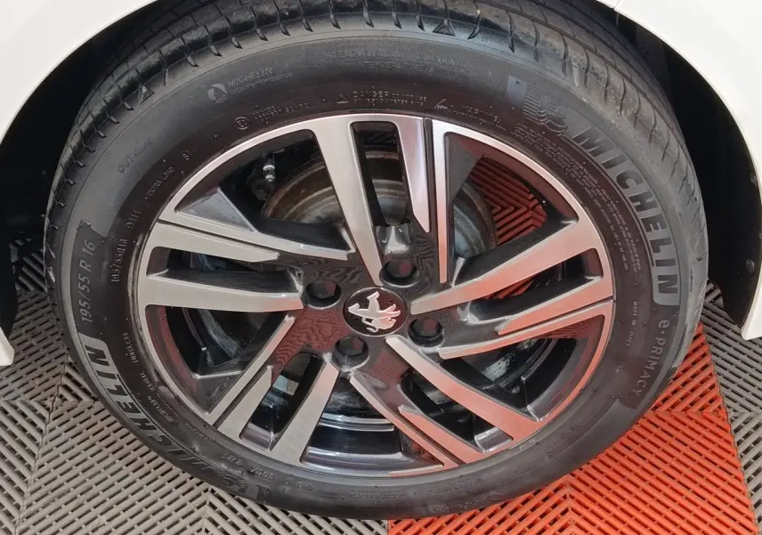 Gros plan sur la roue avant droite d'une Peugeot 208 2023 avec jante alliage noire et argentée, pneu Michelin.