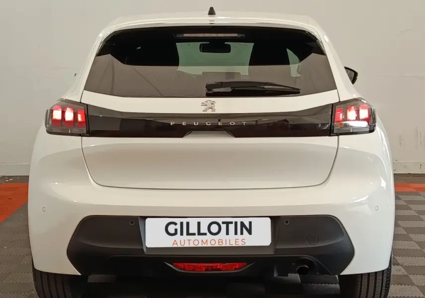 Vue arrière d'une Peugeot 208 blanche 2023 avec feux LED et bande noire distinctive sur le hayon.