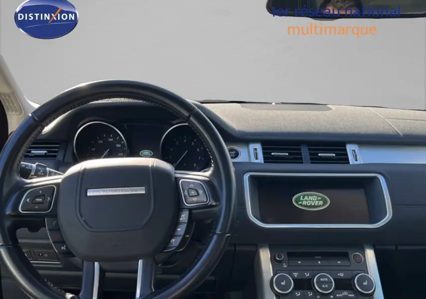 Vue intérieure centrée sur le volant noir et le tableau de bord du Range Rover Evoque 2017 avec écran Land Rover allumé.