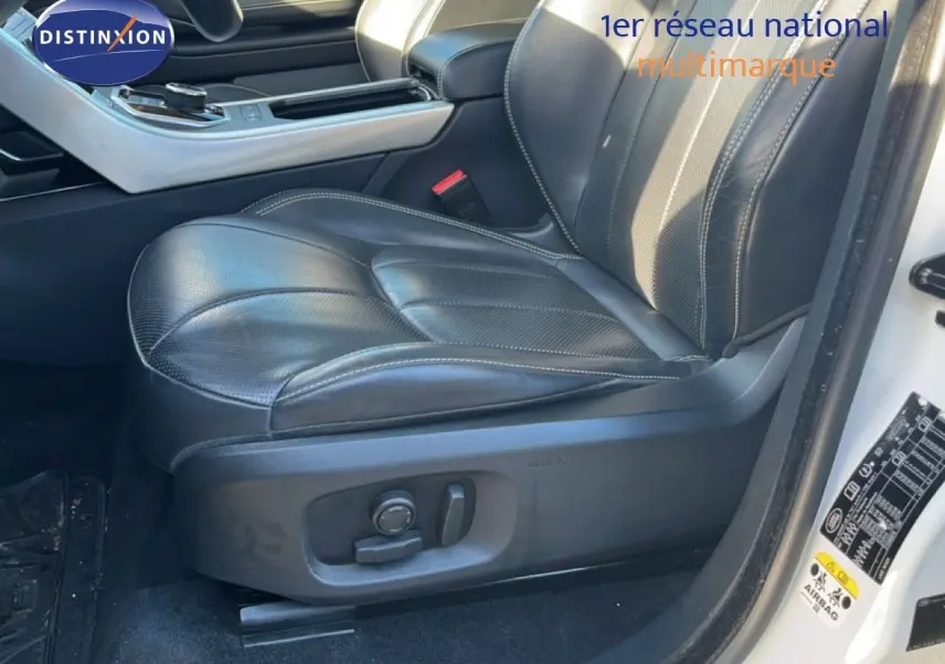 Gros plan sur le siège conducteur en cuir noir du Range Rover Evoque blanc, avec commandes électriques visibles sur le côté.