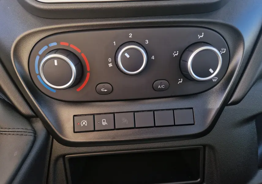 Gros plan sur les commandes de climatisation manuelle du tableau de bord du Iveco Daily Chassis Cabine blanc.