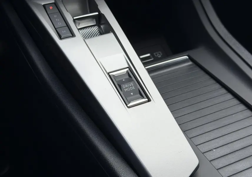 Gros plan sur la console centrale argentée du Peugeot 308 NV Hybrid avec bouton Drive Mode et levier de vitesses automatique.