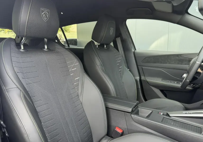 Vue intérieure côté droit sur les sièges tissu noir embossé avec surpiqûres vert Adamite de la Peugeot 308 GT Hybrid 2026.