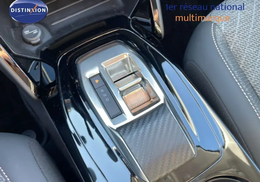 Gros plan sur la console centrale noire laquée de la Peugeot 208 Hybrid 110ch, mettant en valeur la commande de boîte automatique.