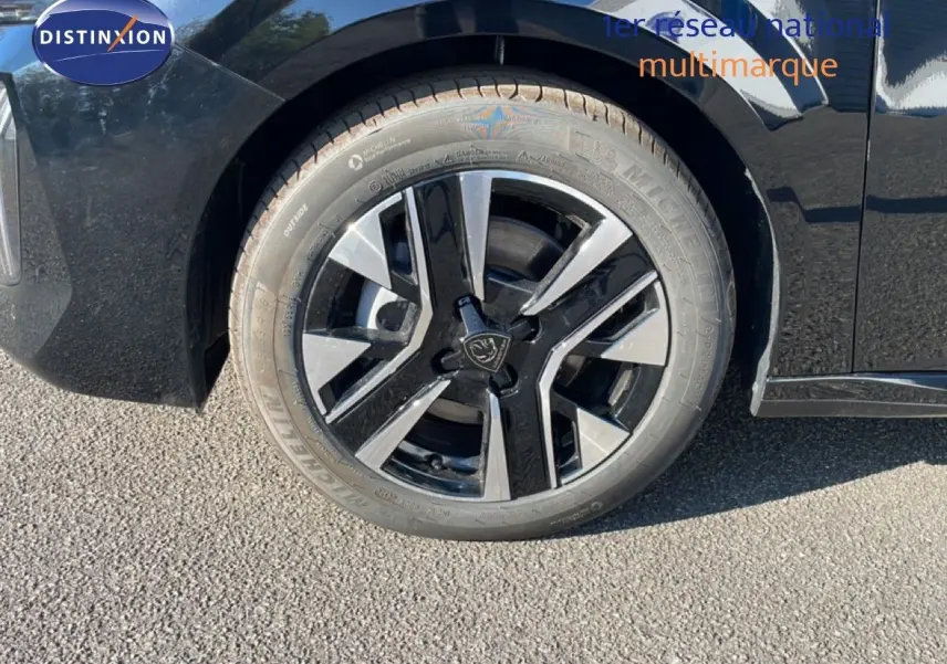 Gros plan sur la roue avant droite d'une Peugeot 208 Hybrid noire avec jante alliage bicolore moderne.