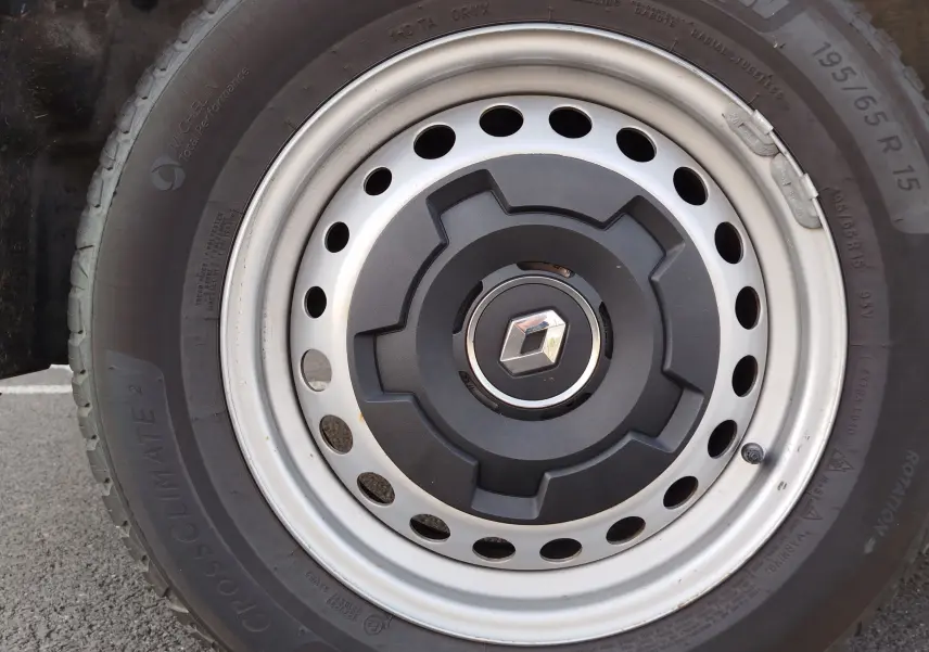 Gros plan sur la roue avant droite du Renault Kangoo blanc minéral, avec jante acier et logo Renault central.