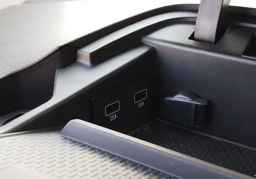 Détail intérieur montrant deux ports USB et une prise 12V dans le coffre du Renault Kangoo blanc minéral 2023.