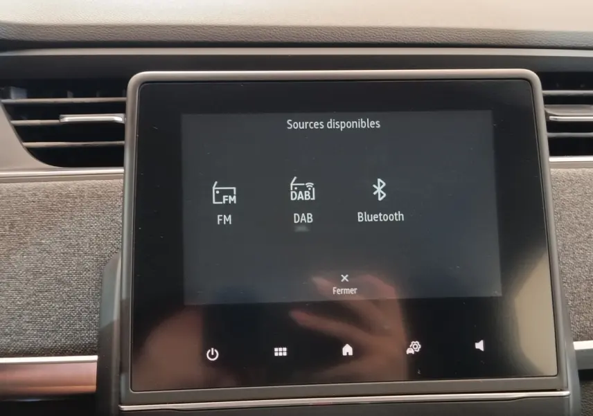 Écran tactile central affichant les sources audio FM, DAB et Bluetooth dans une Renault ZOE Intens blanc, vue intérieure.