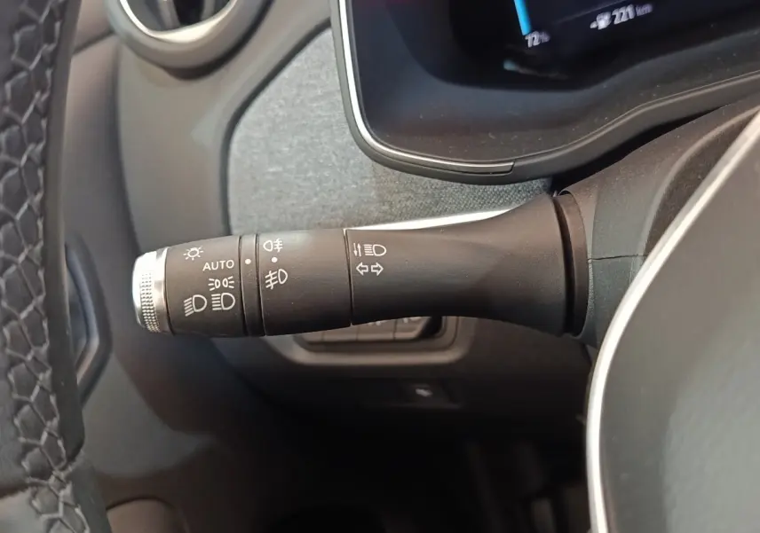 Gros plan sur la commande des feux et clignotants à gauche du volant dans l’habitacle d’une Renault ZOE blanche.