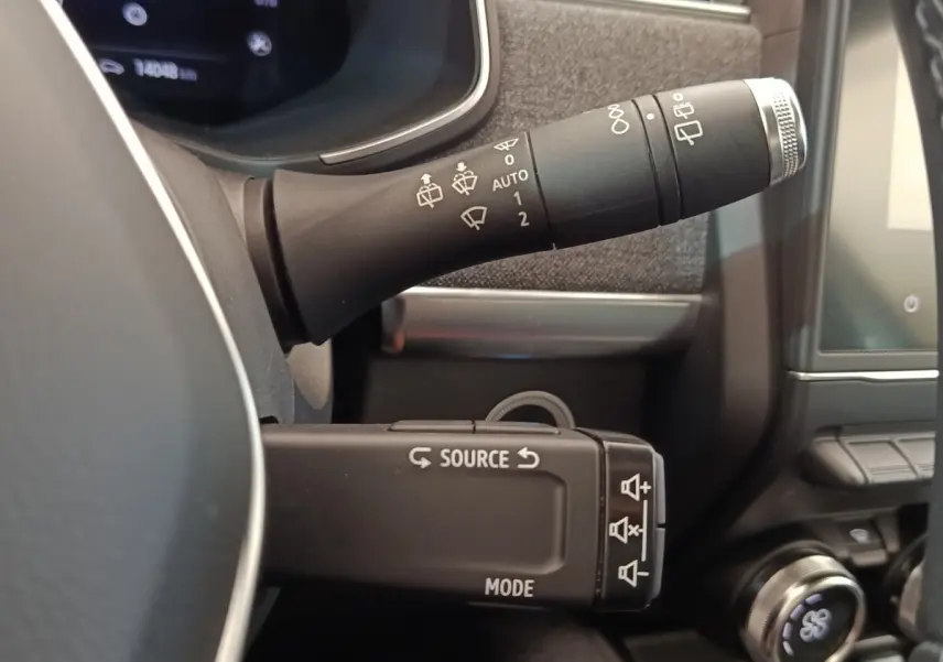 Gros plan sur les commandes au volant de la Renault ZOE Intens R110, intérieur noir avec écran tactile visible.