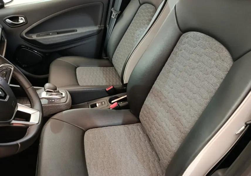 Vue intérieure côté conducteur de la Renault ZOE Intens R110 avec sièges bi-matière gris et noir et volant multifonctions.