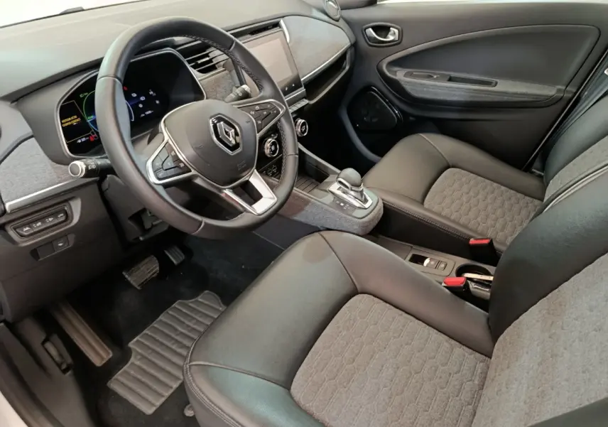 Vue intérieure côté conducteur de la Renault ZOE Intens R110 2021, montrant volant cuir, console centrale et sièges gris et noirs.