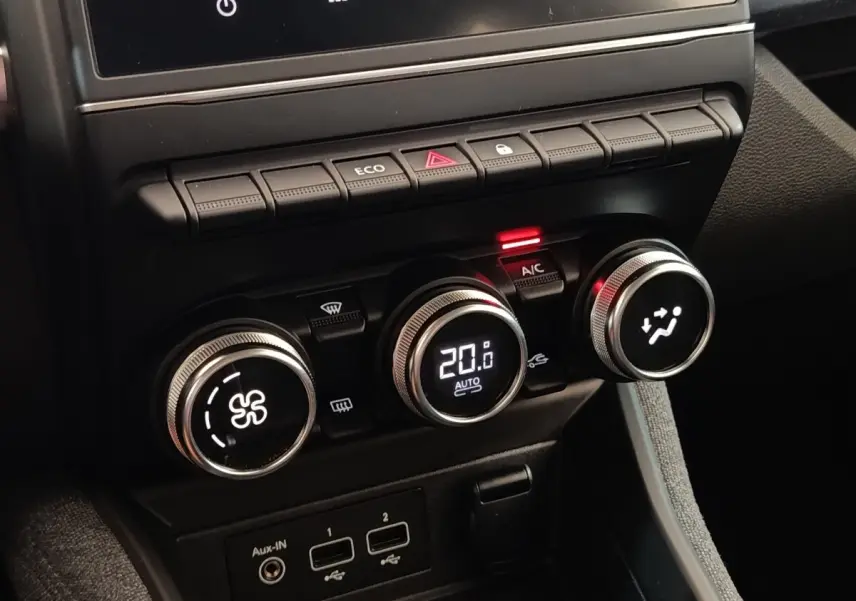 Gros plan sur la console centrale de la Renault ZOE blanche, avec commandes de climatisation digitales et boutons fonctionnels.