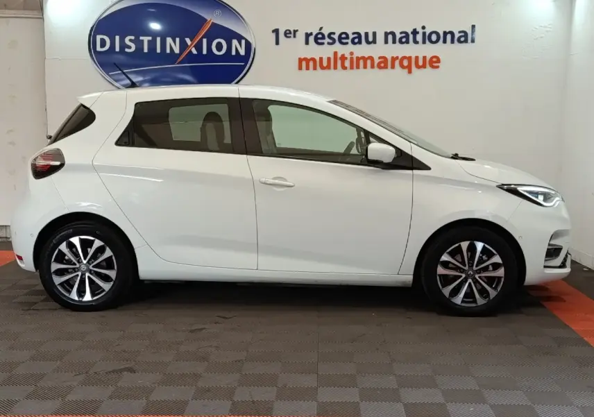 Profil droit d'une Renault ZOE Intens R110 blanche de 2021, avec jantes alliage et feux avant LED visibles.