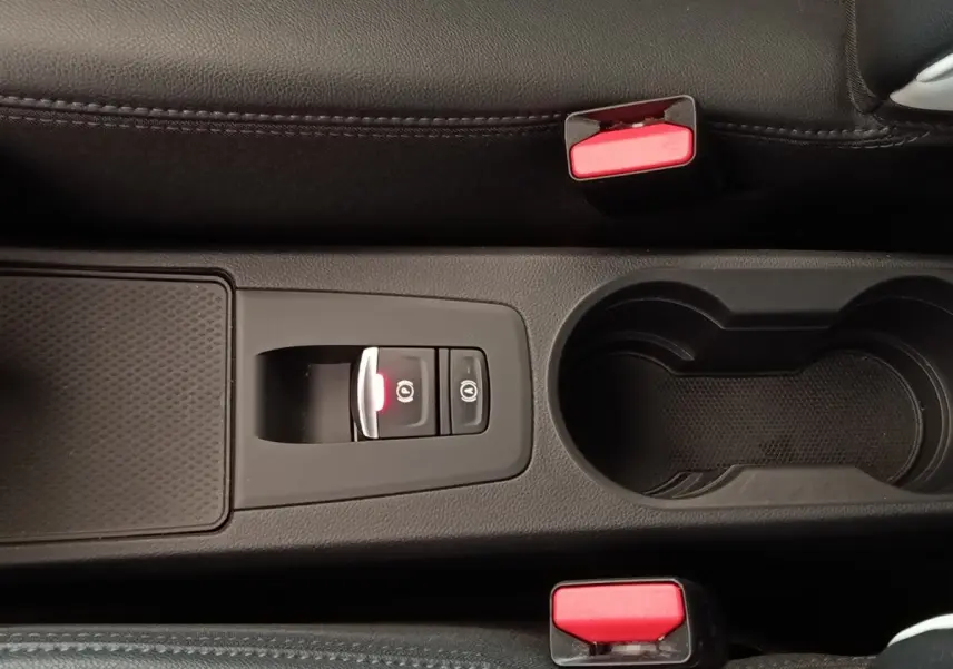 Vue rapprochée de la console centrale noire de la Renault ZOE Intens R110 avec frein à main électrique et porte-gobelets.