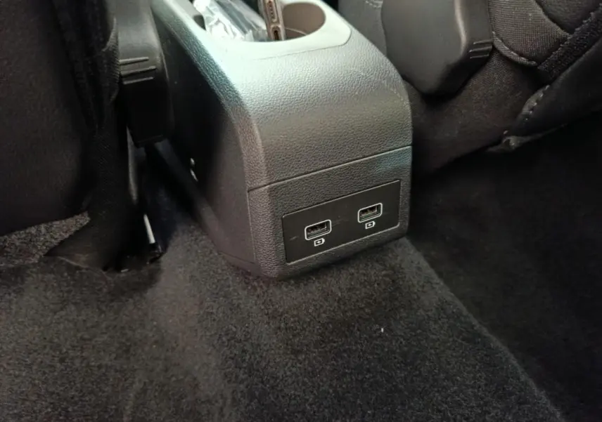 Vue rapprochée des ports USB arrière intégrés à la console centrale noire dans l’habitacle d’une Renault ZOE blanche.