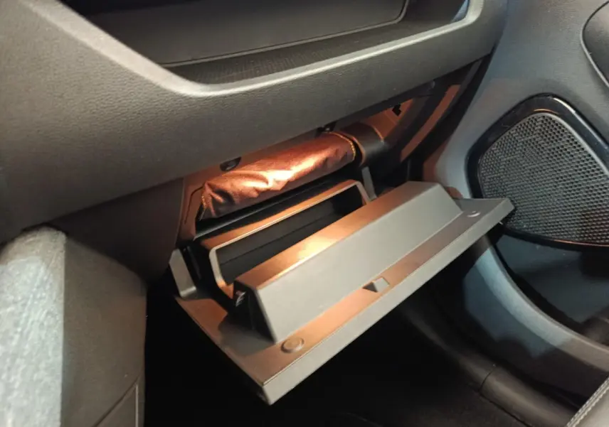 Vue rapprochée de la boîte à gants ouverte côté passager dans l’habitacle sombre d’une Renault ZOE blanche.