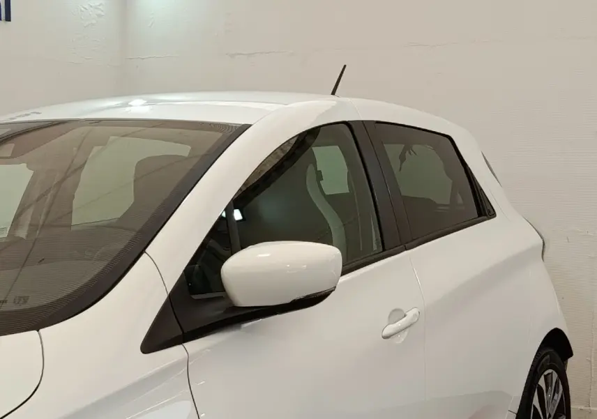 Vue de profil côté gauche sur une Renault ZOE Intens R110 blanche, avec rétroviseur et poignées assortis.