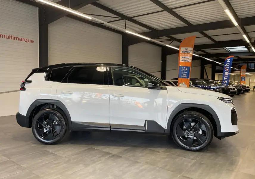 Vue de profil côté gauche du Citroën C5 Aircross blanc Okenite avec toit noir et jantes alliage noires en showroom.