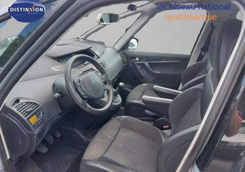 Intérieur avant droit de la Citroën C4 Picasso gris alu 2013, sièges tissu noir et tableau de bord complet.