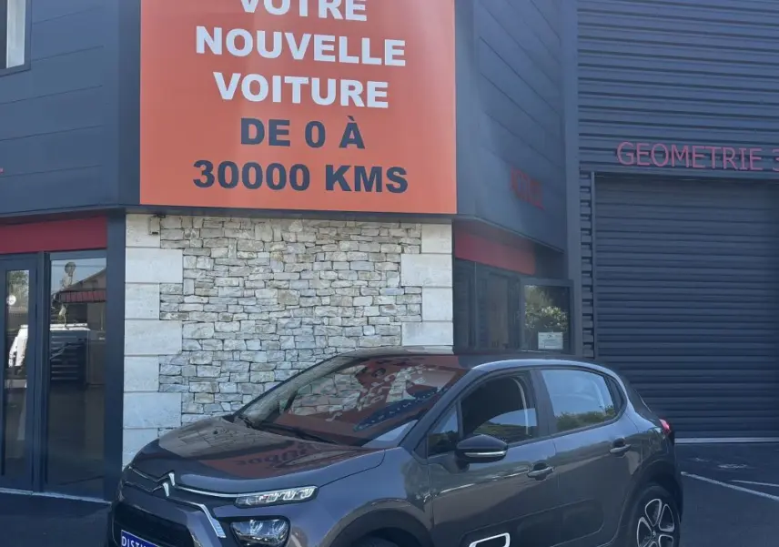 Citroën C3 gris foncé vue 3/4 avant droit, avec signature lumineuse distinctive et jantes stylisées.