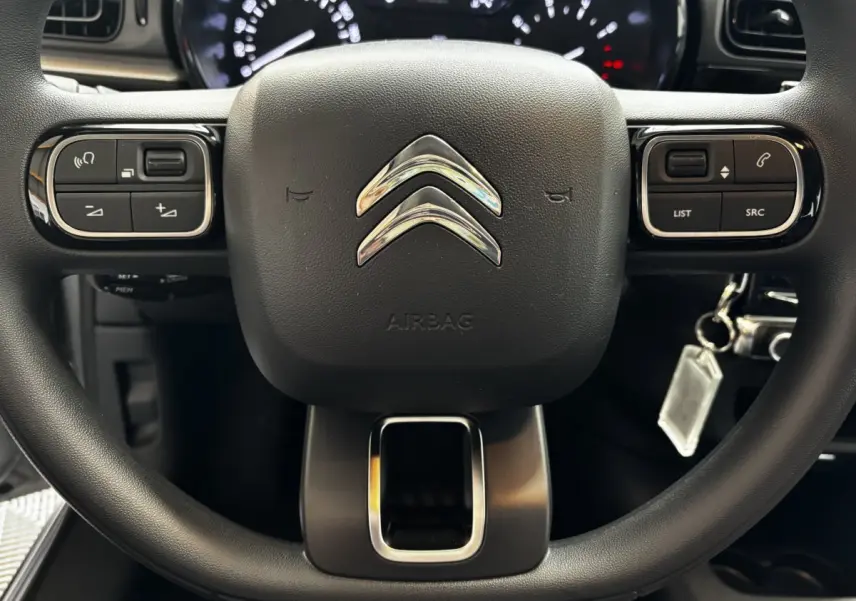 Gros plan sur le volant multifonctions noir de la Citroën C3 PureTech 110, avec commandes intégrées et logo chromé central.