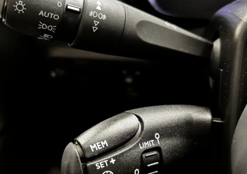Gros plan sur les commandes de régulateur de vitesse et feux du tableau de bord d'une Citroën C3 2024 gris foncé.
