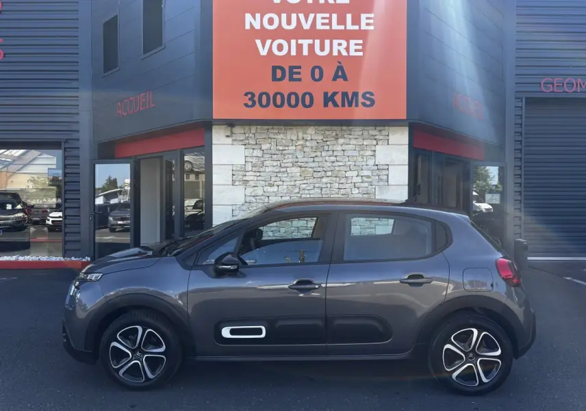 Profil côté gauche de la Citroën C3 2024 gris foncé avec ses jantes distinctives et protections latérales noires.