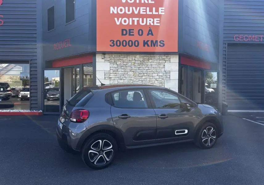 Citroën C3 gris foncé vue de profil côté droit, avec protections latérales blanches et jantes stylisées.