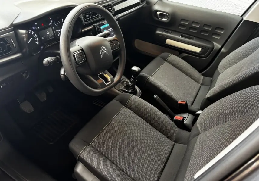 Intérieur avant droit de la Citroën C3 2024 gris foncé, volant multifonction et boîte manuelle visibles.