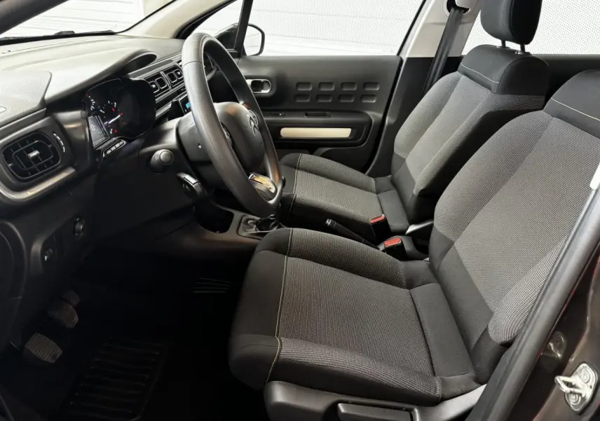 Intérieur avant droit de la Citroën C3 2024 gris foncé, avec sièges tissu et tableau de bord moderne tactile.